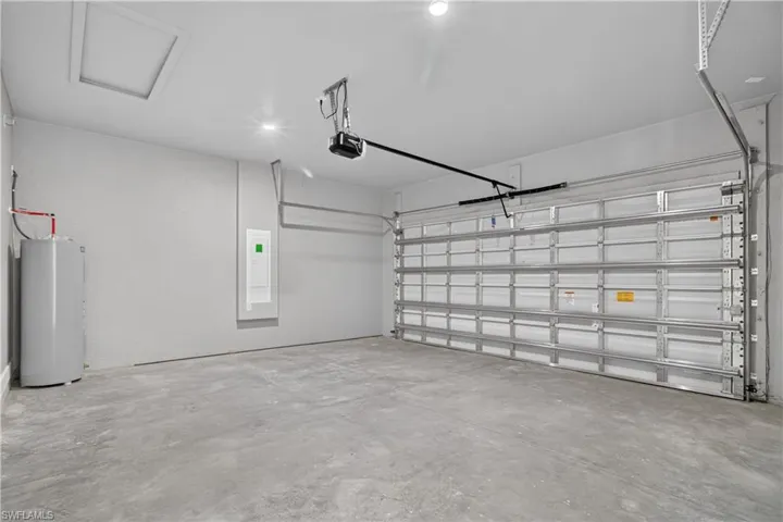 Spacious garage featuring a concrete floor, automatic garage door opener, and a water heater
