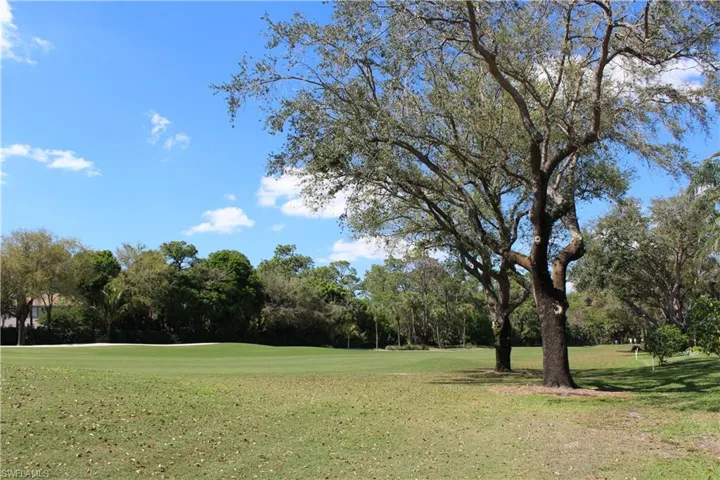 View of property's community with view of golf course and a lawn