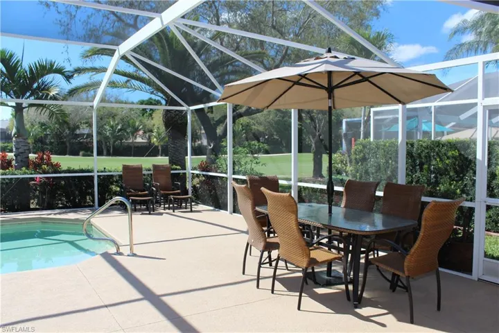 Pool with glass enclosure, outdoor dining space, and a patio area