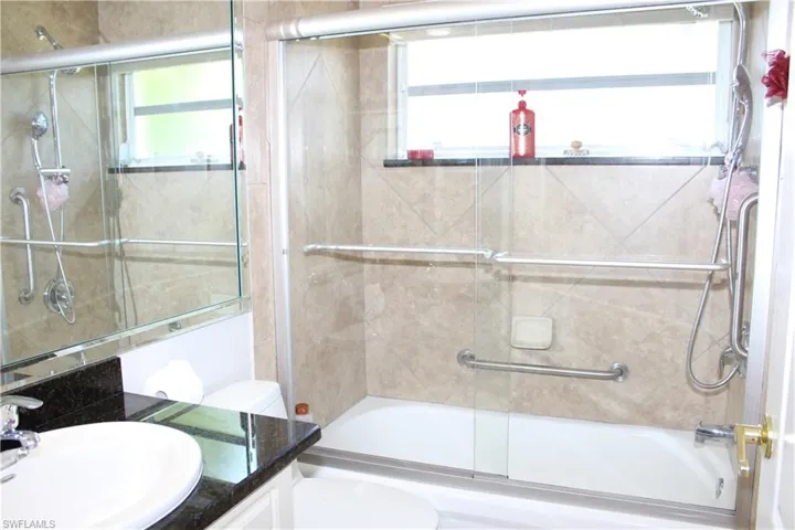 Full bath with bath / shower combo with glass door, vanity, and toilet