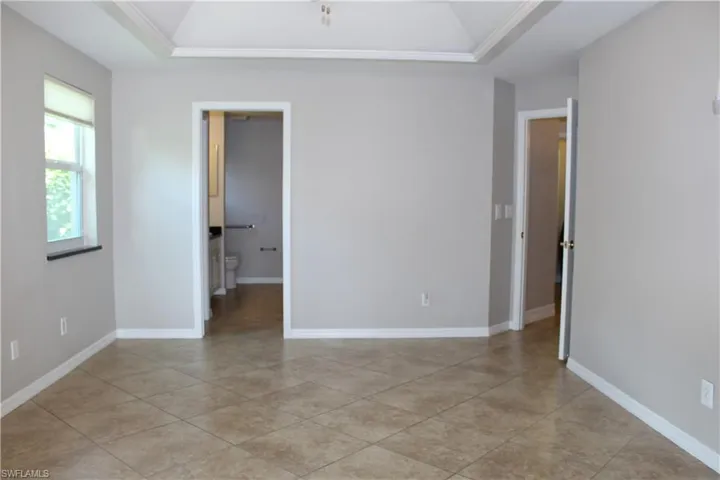 Master Bedroom featuring a tray ceiling, ornamental molding, and light tile patterned floors