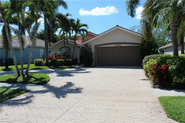 View of front facade featuring decorative driveway, an attached garage, and stucco siding