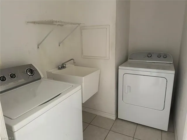 Laundry area featuring light tile patterned floors and baseboards