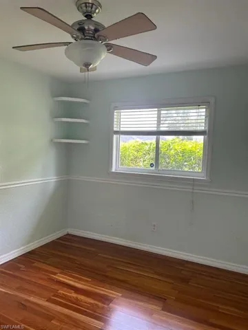 Unfurnished room with ceiling fan and dark wood-style flooring