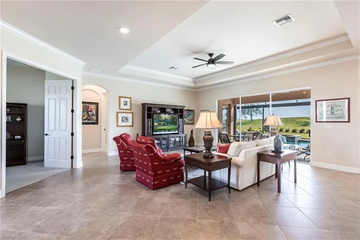 Great room with ceiling fan, tray ceiling, and crown molding.