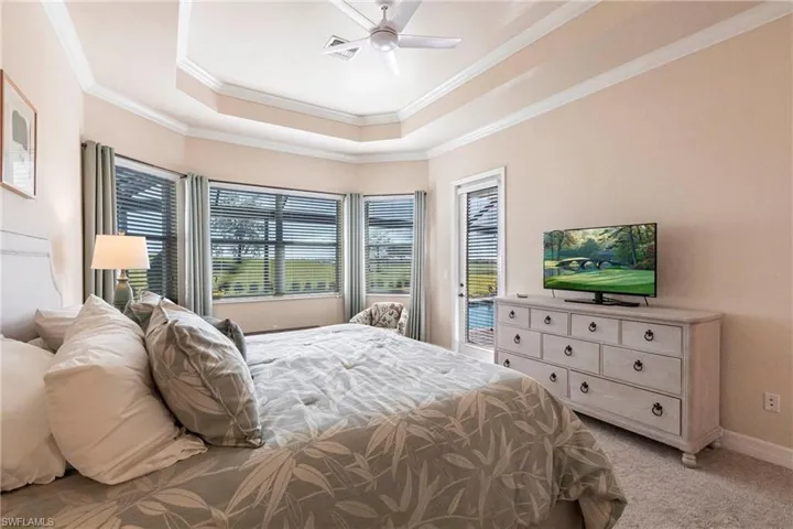 Primary bedroom featuring crown molding, access to exterior, ceiling fan, and a tray ceiling.