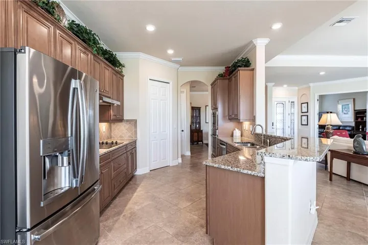 Kitchen featuring built in appliances, stainless steel side by side refrigerator, granite and a neutral backsplash