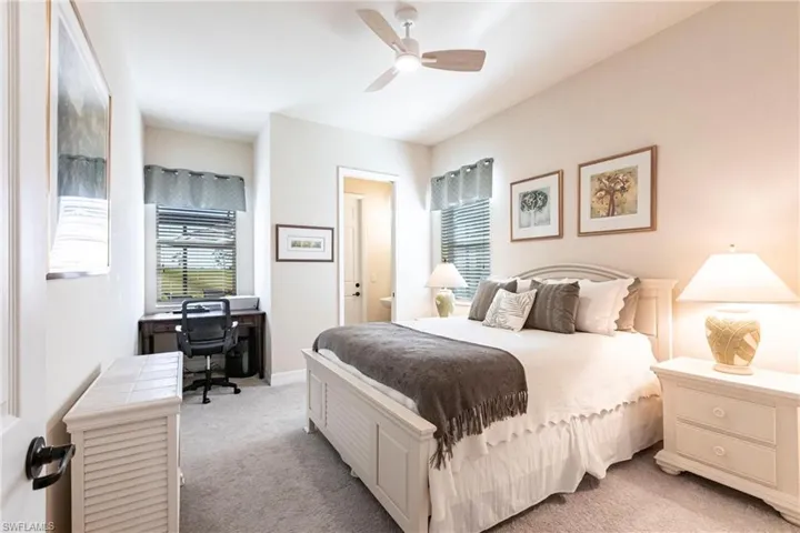 Bedroom #3 featuring ceiling fan, queen bed, desk nook, and 1/2 bath that leads to the pool/lanai.
