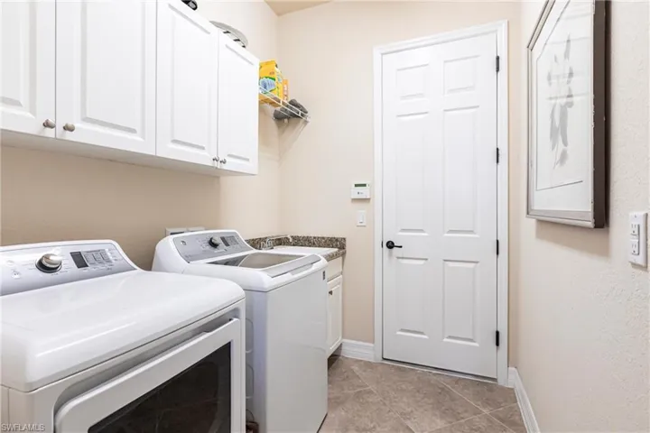 Laundry room with sink, washing machine, dryer, and cabinets