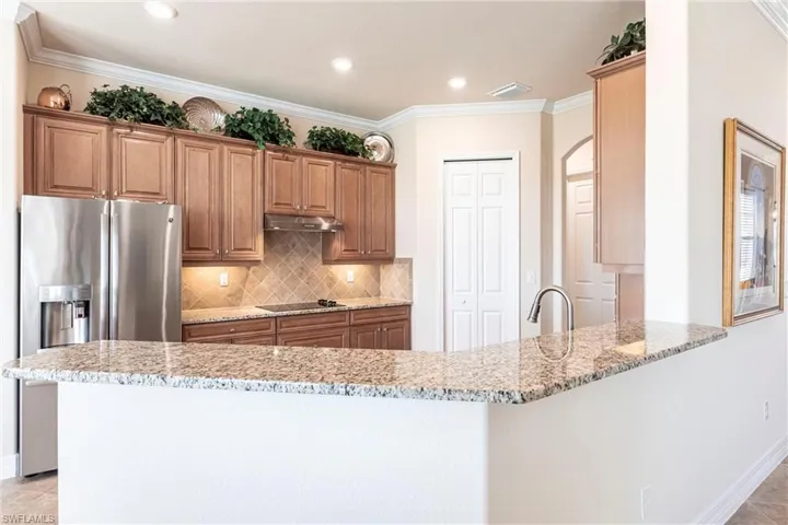 Kitchen featuring crown molding, stainless steel appliances, granite countertops, decorative backsplash, and kitchen peninsula