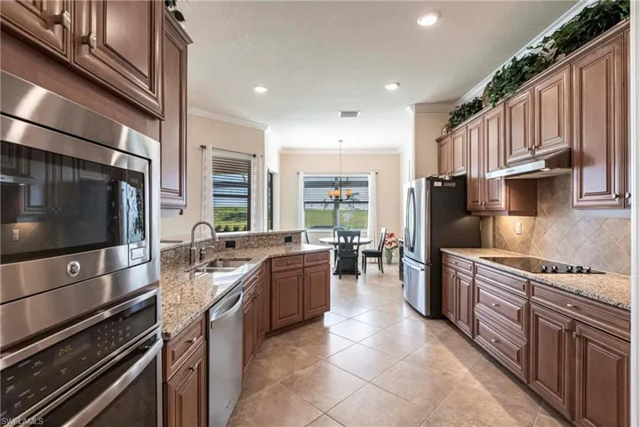 Kitchen with stainless steel appliances, crown molding, hanging light fixtures, and sink