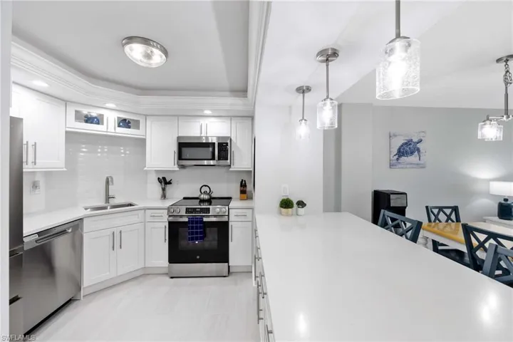Kitchen featuring appliances with stainless steel finishes, decorative backsplash, light countertops, white cabinets, and recessed lighting