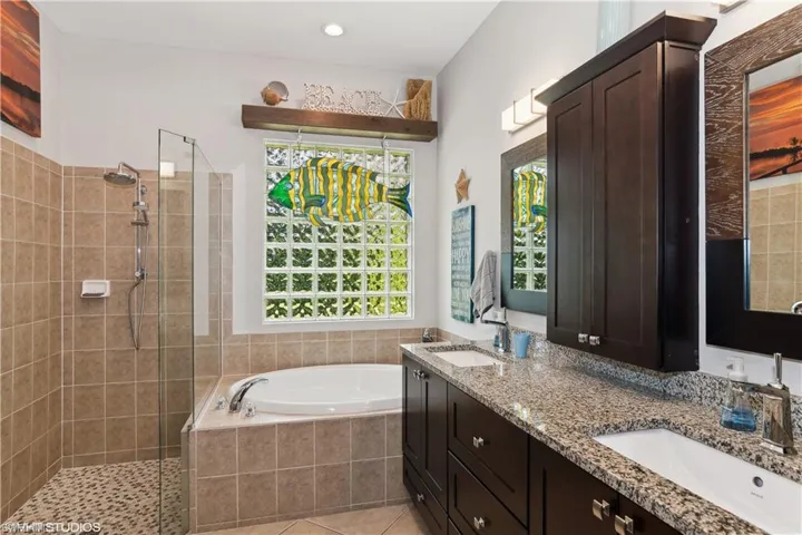 Bathroom featuring large vanity, tile flooring, double sink, and shower with separate bathtub