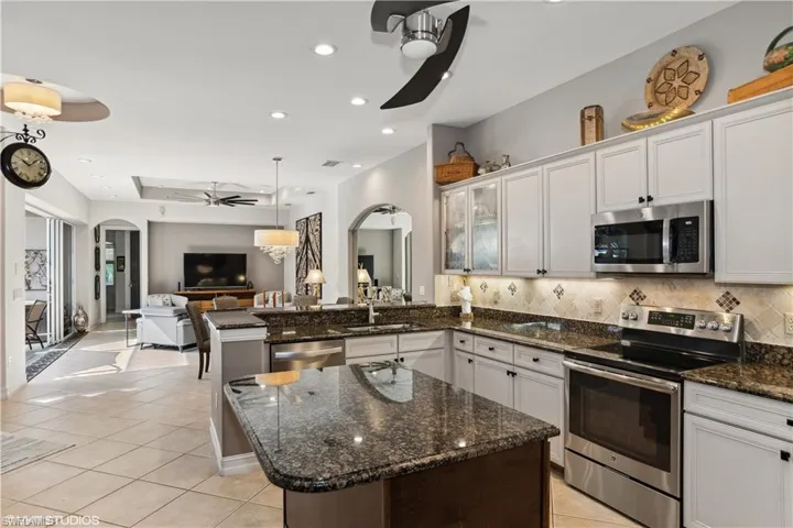 Kitchen with appliances with stainless steel finishes, white cabinetry, tasteful backsplash, and ceiling fan