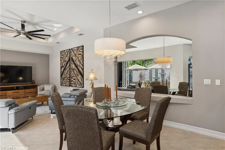 Tiled dining room featuring ceiling fan and a raised ceiling