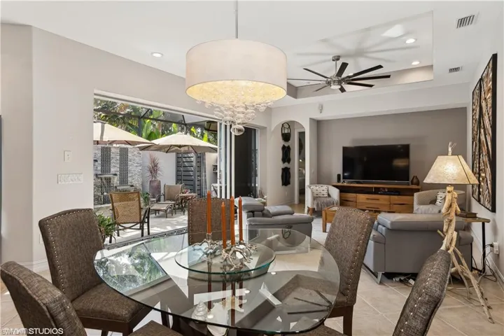 Dining room featuring light tile floors, a raised ceiling, and ceiling fan with notable chandelier