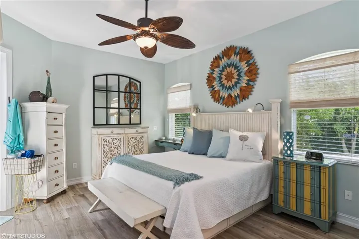 Bedroom with ceiling fan, multiple windows, and hardwood / wood-style floors