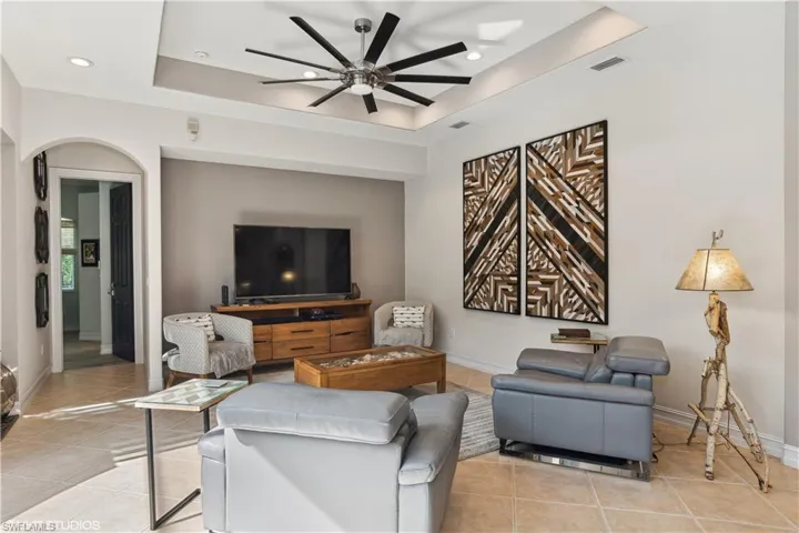 Living room with ceiling fan, a tray ceiling, and light tile floors
