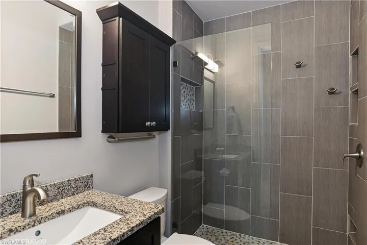 Bathroom with a tile shower, oversized vanity, and toilet