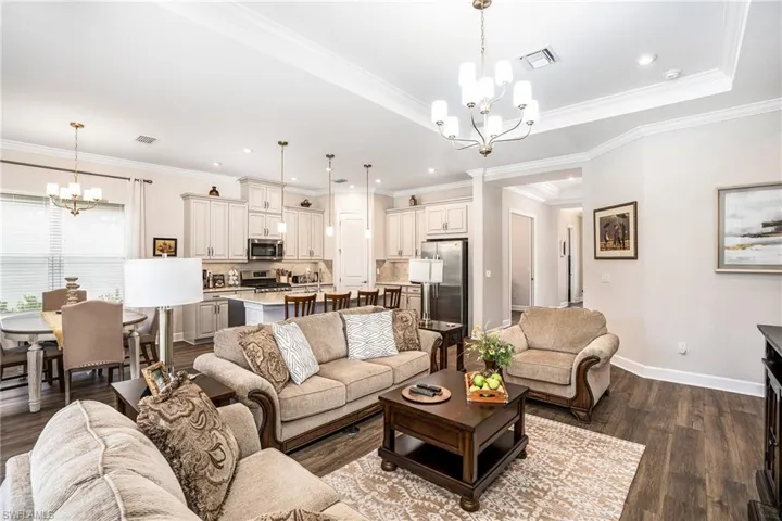 Living area with a chandelier, dark wood-type flooring, ornamental molding, and recessed lighting
