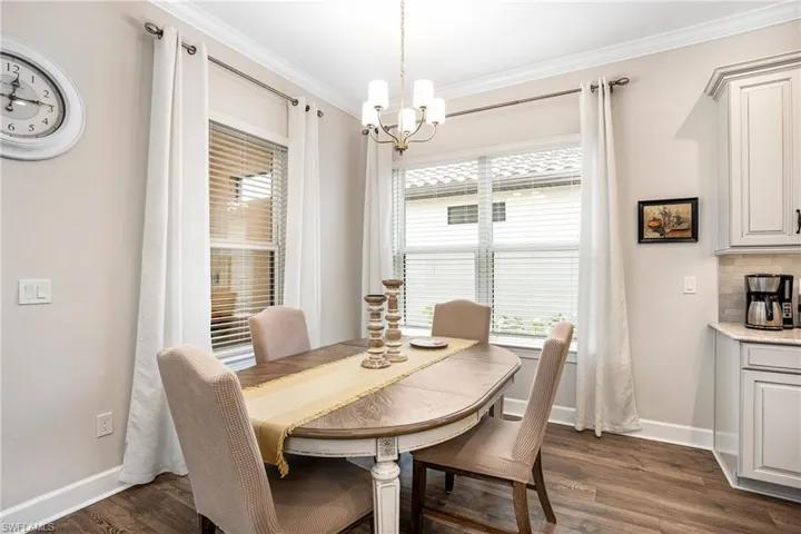 Dining space featuring crown molding, dark wood-style flooring, and a chandelier