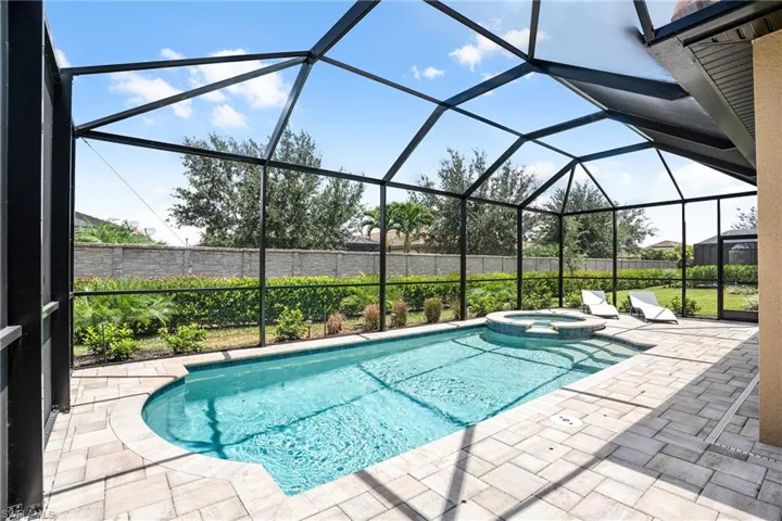 View of pool featuring a sunroom, glass enclosure, a pool with connected hot tub, and a patio area
