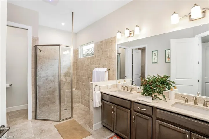Full bathroom with a stall shower, light tile patterned floors, and double vanity