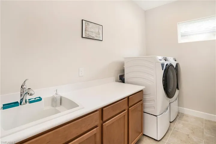 Washroom with washing machine and dryer, cabinet space, and light tile patterned flooring