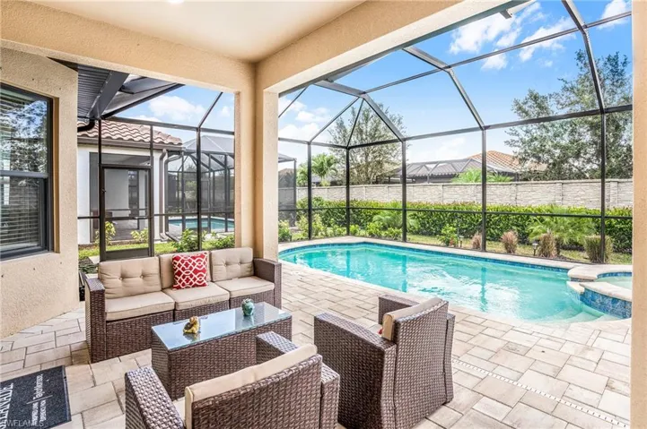 View of swimming pool with a patio area, a sunroom, a pool with connected hot tub, a lanai, and an outdoor living space