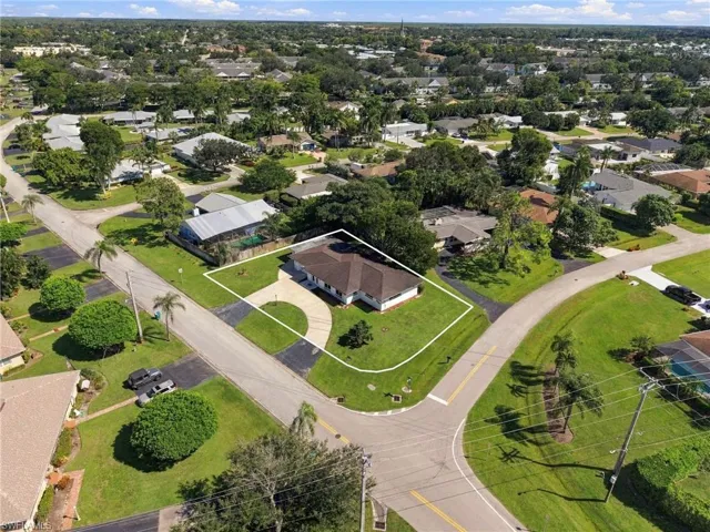 Corner lot property featuring a single-story residence, hipped roofline, and curved concrete driveway
