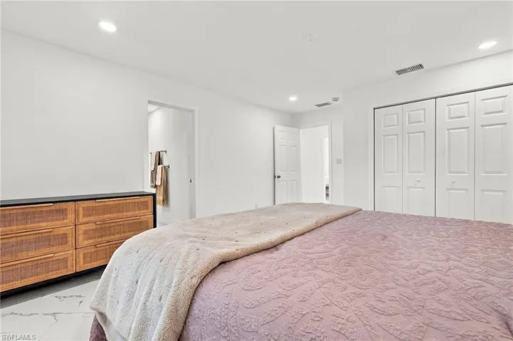 Interior space featuring white-toned stone-finish flooring, recessed lighting, and a bi-fold closet with white panel doors