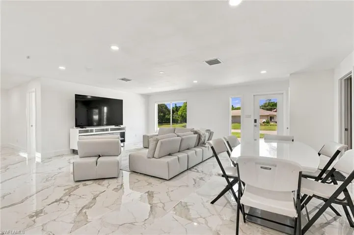 Open-concept living space featuring large-format stone-finish flooring, recessed lighting, and multiple windows