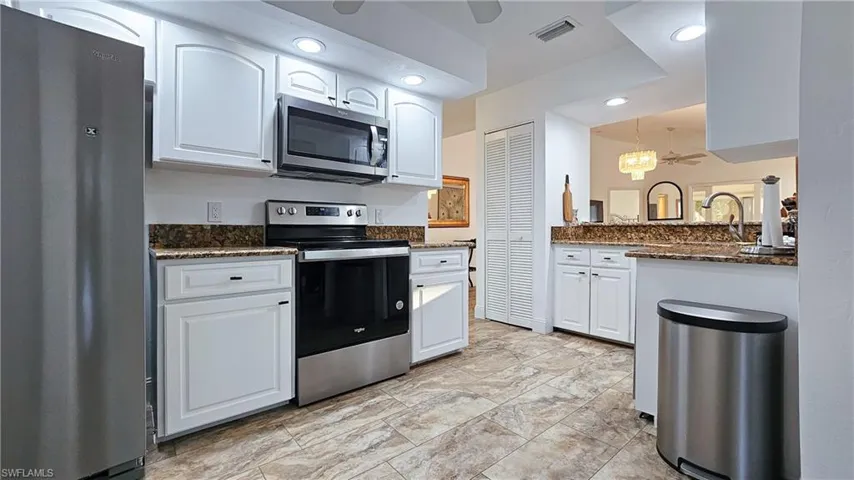 Kitchen with appliances with stainless steel finishes, white cabinetry, dark stone counters, ceiling fan, and recessed lighting