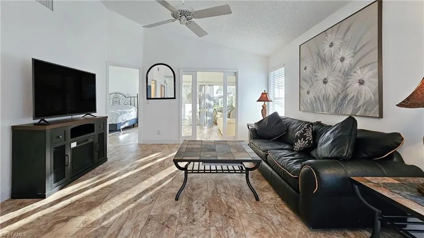 Living room featuring a textured ceiling, a ceiling fan, and high vaulted ceiling