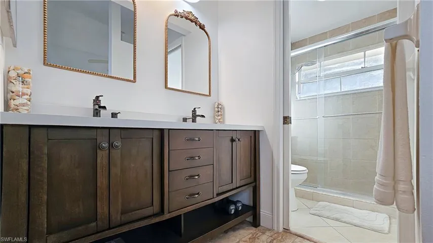 Full bathroom featuring double vanity, a stall shower, and light tile patterned floors