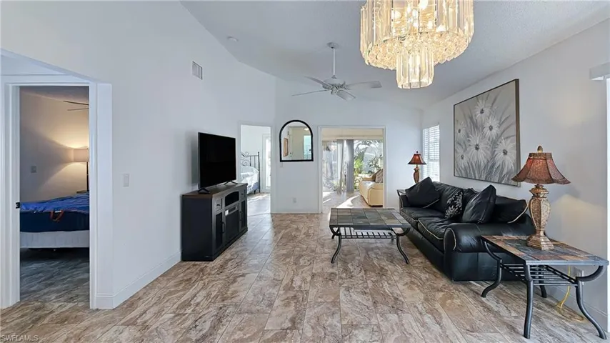 Living room with a ceiling fan, a chandelier, and high vaulted ceiling