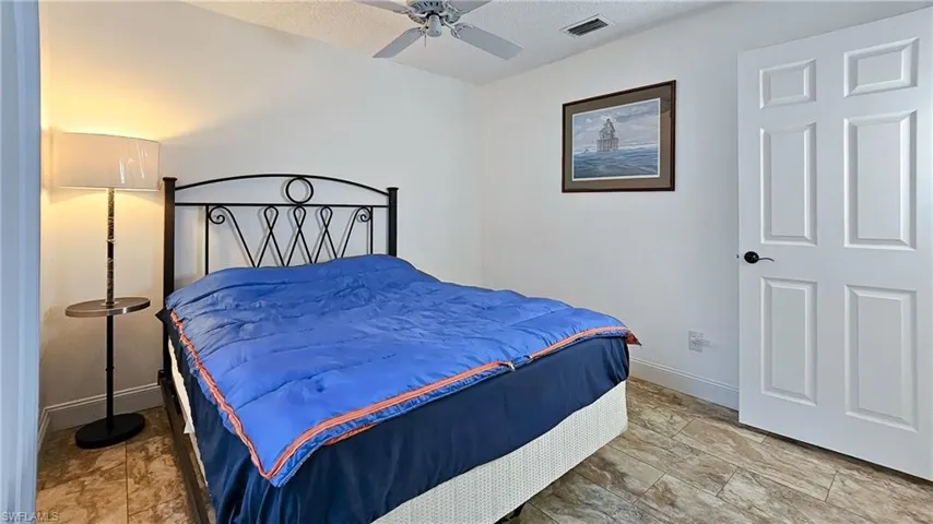 Bedroom featuring a ceiling fan, a textured ceiling, and stone finish flooring