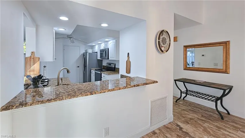 Kitchen with appliances with stainless steel finishes, recessed lighting, white cabinets, dark stone countertops, and ceiling fan