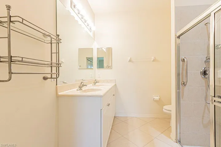 Bathroom featuring double vanity, a stall shower, and light tile patterned floors