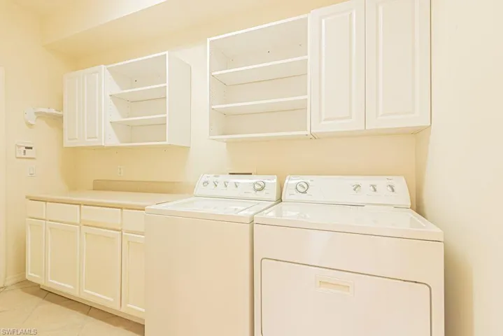 Laundry area featuring cabinet space, separate washer and dryer, and light tile patterned floors
