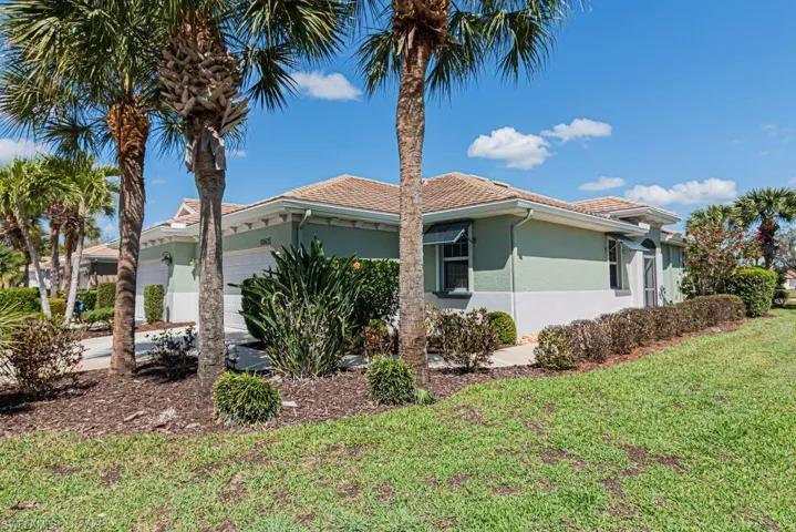 View of property exterior with a garage, stucco siding, a yard, and a tiled roof