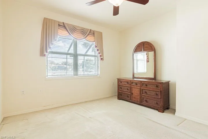 Unfurnished bedroom with multiple windows, light carpet, and a ceiling fan