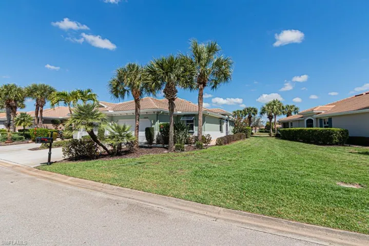 View of front of home with a front yard, a tile roof, an attached garage, and driveway