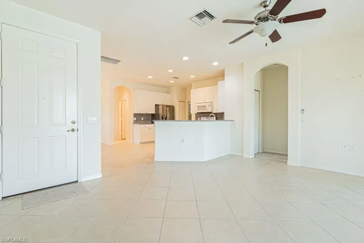 Unfurnished living room with arched walkways, recessed lighting, light tile patterned floors, and ceiling fan