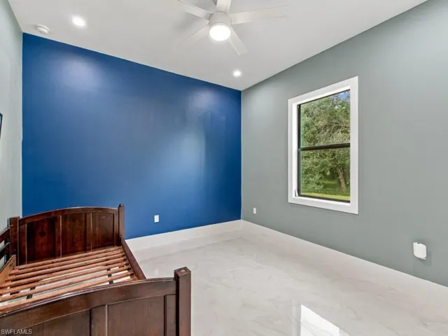 Interior space featuring large-format tile flooring, a dual-tone accent wall, a single-hung window with dark frames, and a ceiling-mounted light fixture with a fan