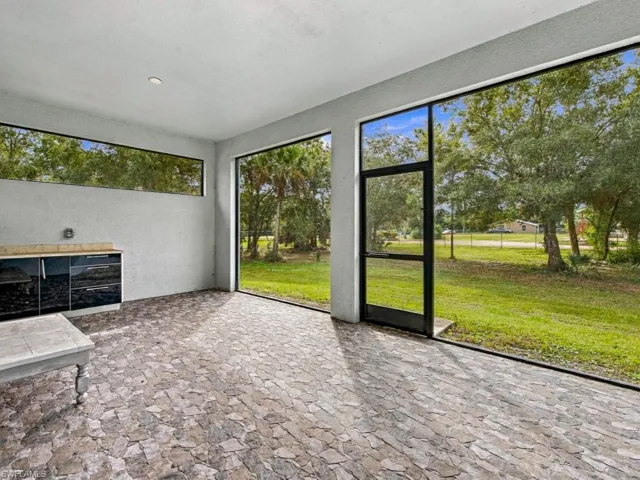 Enclosed patio featuring flagstone-style flooring, floor-to-ceiling glass paneling, built-in cabinetry with a stone countertop, and a glass-paneled screen door