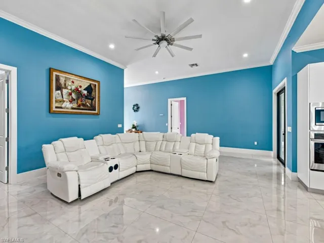 Vaulted ceilings, large-format tile flooring, multi-blade ceiling fan, recessed lighting, and built-in stainless steel wall oven