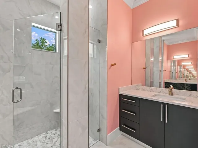 Walk-in shower with floor-to-ceiling stone-finish tile, glass enclosure, and a built-in corner bench