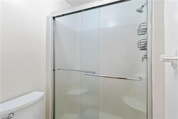 Bathroom featuring toilet and a shower with shower door