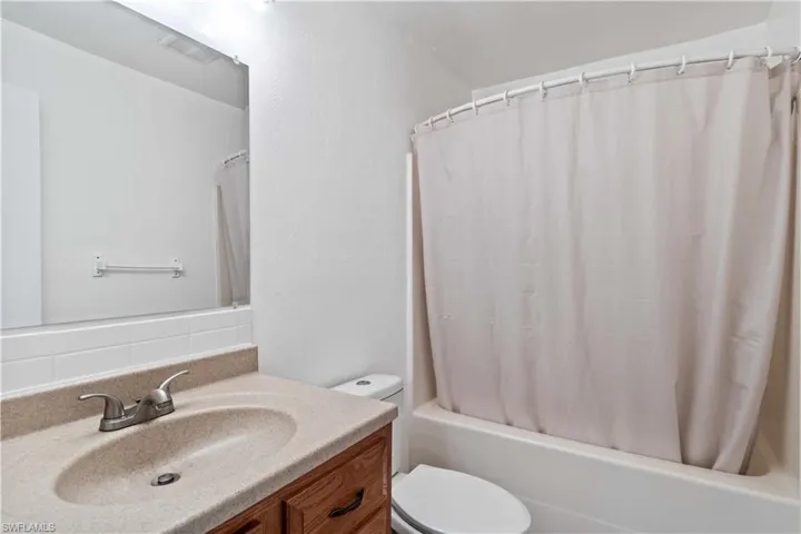 Full bathroom with vanity, toilet, decorative backsplash, and shower / bath combo